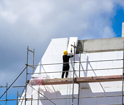 Hombre instalando paneles de poliestireno en una fachada - Aislamiento térmico