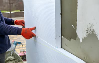 Persona pegando un panel de poliestireno en una pared externa - Aislamiento térmico