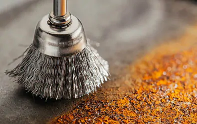 Cepillo de alambre para taladro sobre hoja de metal con óxido