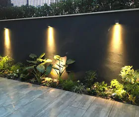 Cerca perimetral de concreto y acero con jardinera iluminada